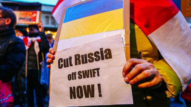 Gente protestando y pidiendo la exclusión de Rusia de la red SWIFT.
