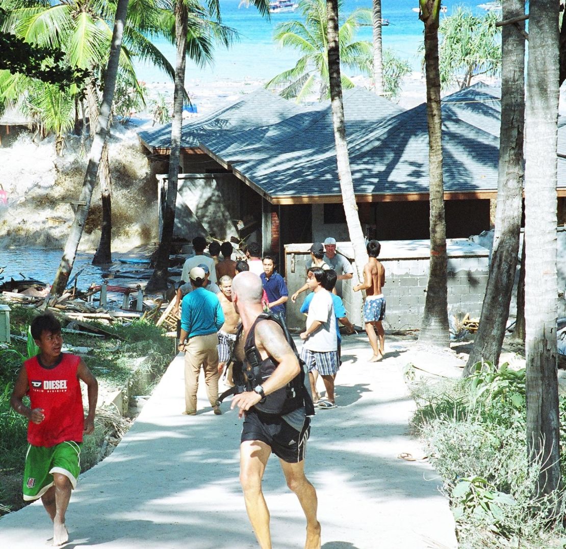 La gente huye cuando una ola de tsunami golpea la costa de una isla de Tailandia.