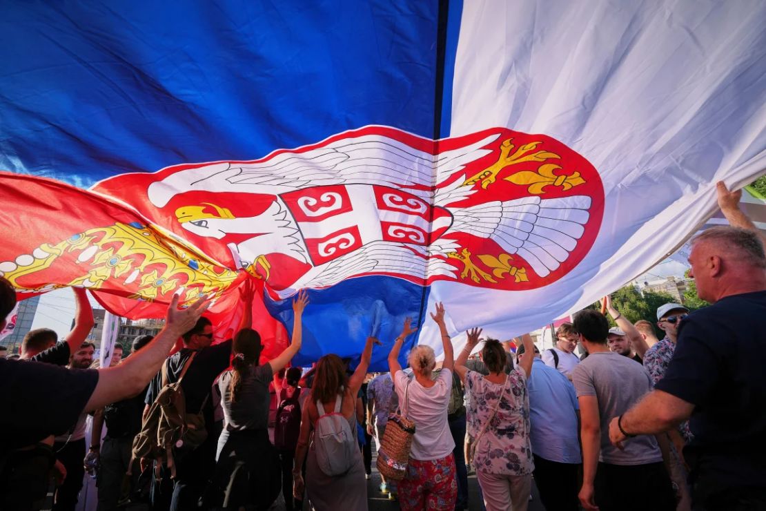 La gente camina bajo una gran bandera serbia durante una gran manifestación antigubernamental en Belgrado el sábado.