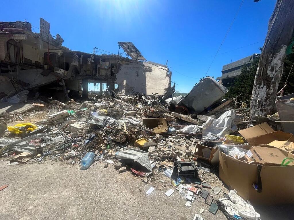 Una toma amplia de un edificio destruido y escombros en Líbano bajo un cielo azul brillante, mostrando las consecuencias del conflicto.